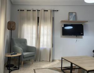 a living room with a chair and a television at Casa Rural Fuente Vieja in Malpartida de Plasencia