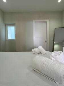 a white bedroom with two towels on a bed at Navas 202 Elegant Suite in Granada