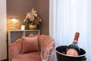 Una botella de vino en un cubo sobre una silla con vasos. en Querini Suite Roma, en Roma