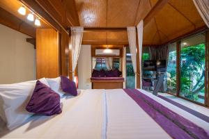 Un dormitorio con una gran cama blanca con almohadas moradas. en Pattaya Bungalow I, Totally Private Pool, en Pattaya South