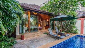 un patio con una silla y una sombrilla junto a la piscina en Pattaya Bungalow I, Totally Private Pool, en Pattaya South
