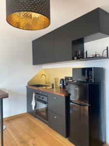 a kitchen with black cabinets and a black refrigerator at Le cœur de St Martin in Bréhal +6 photos