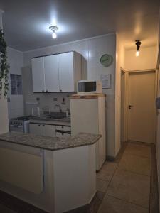a kitchen with white cabinets and a counter with a microwave at Predio frente a praia ap 615 in Praia Grande