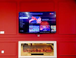 a flat screen tv above a fireplace in a red wall at Royal Reside by StayMehman in Rawalpindi