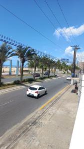 a white car driving down a street with palm trees at Predio frente a praia ap 615 in Praia Grande
