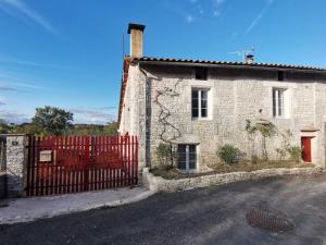 een oud stenen huis met een rood hek bij Épi Cottage in Coulgens