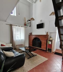 een woonkamer met een bank en een open haard bij Épi Cottage in Coulgens