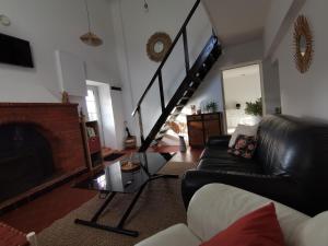 een woonkamer met een zwarte leren bank en een open haard bij Épi Cottage in Coulgens