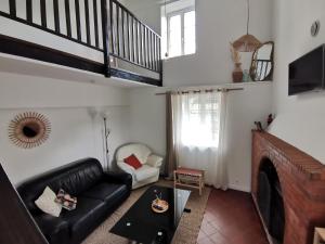 een woonkamer met een zwarte leren bank en een open haard bij Épi Cottage in Coulgens