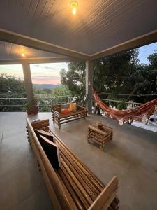 a porch with benches and a hammock on a balcony at Suítes Preguiça in Sao Jorge