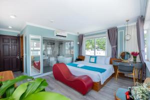 a bedroom with a bed and a desk and a red chair at 3H GRAND HOTEL Vũng Tàu in Vung Tau
