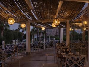 a patio with tables and chairs and chandeliers at Atlantica Imperial Resort - Adults Only in Kolimbia