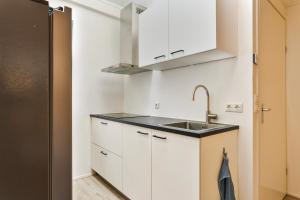 a kitchen with white cabinets and a sink at Knusse woning in Joure! in Joure