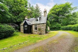 una vecchia casa in pietra in mezzo a una strada di Red Squirrel Cottage, Family & Pet Friendly Adventure Retreat, Strathdon, Aberdeenshire a Towie