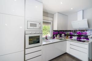 a white kitchen with purple flowers on the counter at Villa Diana 2 Zaton in Zaton