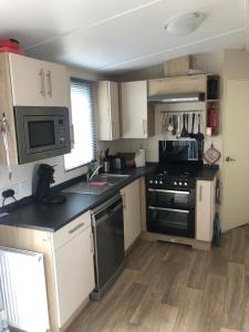 una cucina con armadi bianchi e un forno a piano cottura nero di Chalet ZeeWave I 6 Personen I Renesse I Niederlande a Renesse