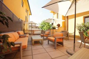 un patio extérieur avec des chaises, des tables et des parasols dans l'établissement Albergo Celide, à Lucques
