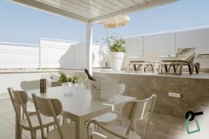 a white table and chairs in a room with windows at Hotiday Apartments Cefalù in Cefalù