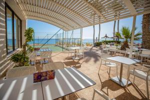 patio ze stołami i krzesłami oraz oceanem w obiekcie Hotel Servigroup La Zenia 4 Sup w mieście Playas de Orihuela