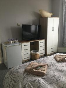 a bedroom with a bed with a television and a dresser at Whitecliff View in Sandown