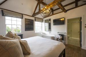 a bedroom with a bed and a bathroom with a tub and a sink at Tavern Townhouse in Henley on Thames