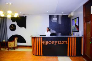 a woman standing at a reception desk in a room at The Country Inn Hotel in Kigali