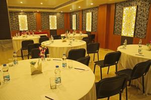 una sala de conferencias con mesas y sillas blancas y ventanas en Hotel Sonar Tori, en Agartala