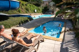 a group of people sitting in chairs in a swimming pool at Camping la Source in Thérondels