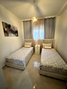 a bedroom with two beds and a window at Appartement cosy à 5 min de la plage Sidi Kacem in Hajreien