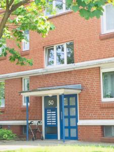 a brick building with a blue door in front of it at Welcome to Messe! Two-bedroom SmartApartment &Balcony in Hannover
