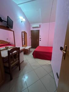 a room with a red bed and a table in it at Hotel Canada in Falerna Marina