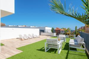 Un patio con sillones blancos y césped. en MEDANO4YOU La Terraza del Sol, en El Médano 43 fotos más