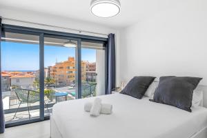 Un dormitorio con una cama blanca y una ventana grande. en MEDANO4YOU La Terraza del Sol, en El Médano