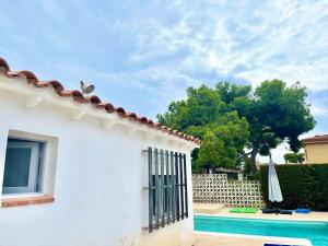 a white house with an umbrella next to a pool at Holiday Beach Home Rincón del Mar in Cunit