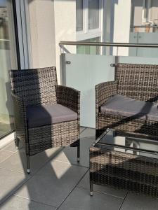 two wicker chairs and a glass table on a balcony at Sonnenblick Apartment in Künzelsau
