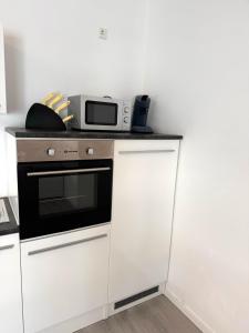 a kitchen with white cabinets and a microwave on a counter at Sonnenblick Apartment in Künzelsau +3 photos