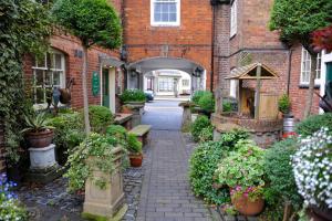 an alley in a brick building with flowers and plants at The Greyhound Coaching Inn in Lutterworth
