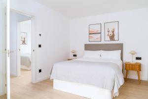 a white bedroom with a white bed and a mirror at Limehome Santiago de Compostela in Santiago de Compostela
