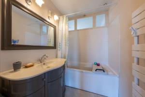 Un baño con lavabo, bañera y espejo. en La Raboliote -Maison 3 chambres- jardin - 15 min Parc Fédéral Lamotte - CAUTION OBLIGATOIRE, en Brinon-sur-Sauldre