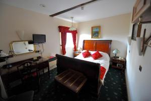 a bedroom with a bed with red pillows and a television at The Greyhound Coaching Inn in Lutterworth