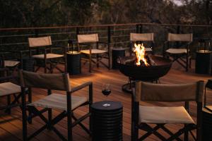 a fire pit on a deck with chairs and a glass of wine at Thornybush Simbambili Lodge in Sabi Sand Game Reserve