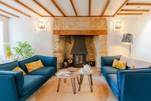 a living room with blue couches and a fireplace at Gable Cottage in Meysey Hampton