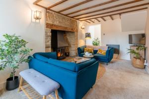 a living room with a blue couch and a fireplace at Gable Cottage in Meysey Hampton
