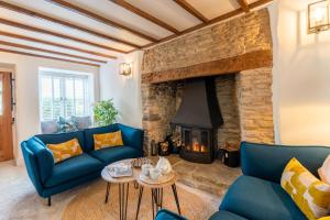 a living room with blue couches and a fireplace at Gable Cottage in Meysey Hampton