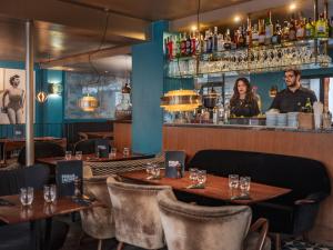 a restaurant with wooden tables and chairs and a bar at Hôtel Edgar & Achille in Paris