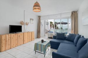 プエルト・デル・カルメンにあるVistamarの青いソファとテレビのあるリビングルーム