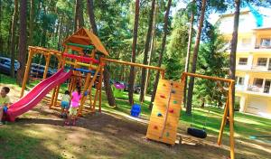 two children playing on a playground in a park at Apartament Blue Mare Łukęcin Spacerowa 6 in Łukęcin