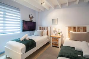 Un dormitorio con dos camas y un televisor de pantalla plana. en Apartment near Hout Bay Harbour, en Ciudad del Cabo