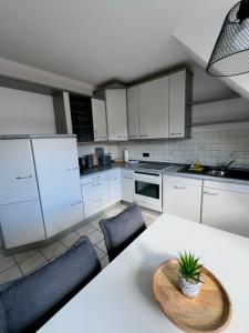 诺德代希Casa del Sol - Ferienwohnung Norddeich的配有白色橱柜、桌子和椅子的厨房