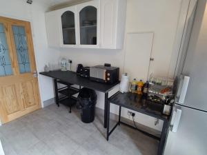 a kitchen with a black counter and a refrigerator at QUICK STOP-GATWICK STAY, Triple room in Ifield +8 photos